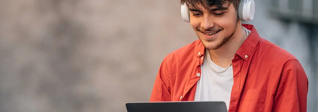 Young man on laptop wearing headphones.