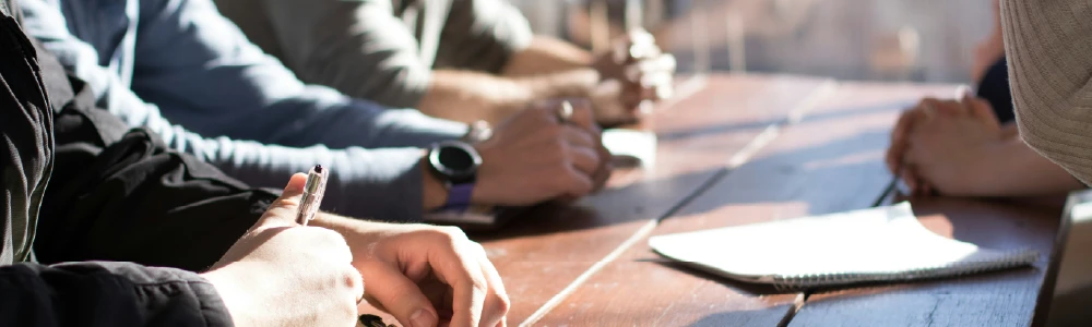 Hands folded at a conference table during meeting.