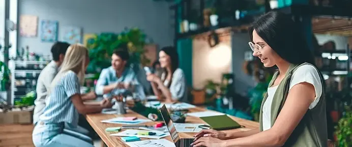 Young open office with girl on laptop in foreground